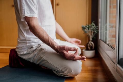 Mann sitzt im Schneidersitz auf einem Yoga-Kissen