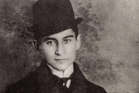 Franz Kafka trägt einen Hund und einen Mantel