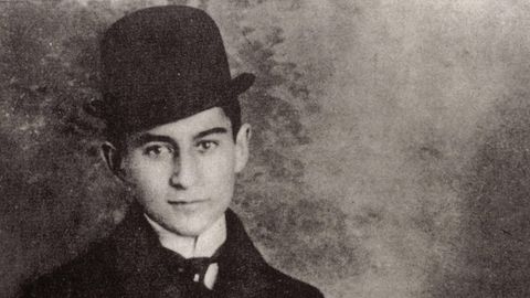 Franz Kafka trägt einen Hund und einen Mantel