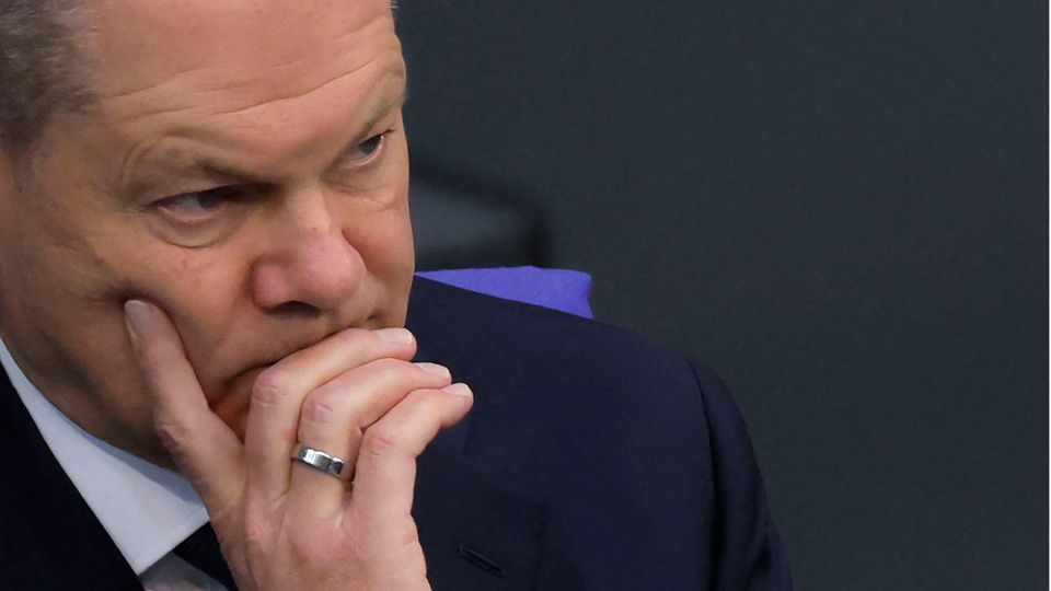 Olaf Scholz sitzt im Bundestag und stützt beim Zuhören seinen Kopf auf seine rechte Hand