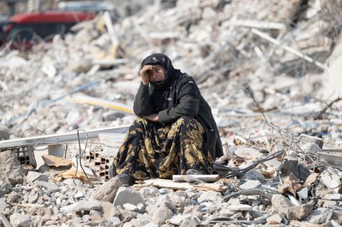 Eine Frau sitzt nach dem Beben in der Türkei und in Syrien in der Stadt Antakya zwischen Trümmern.