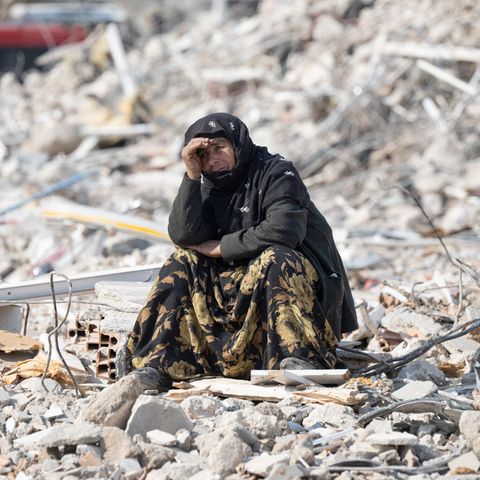 Eine Frau sitzt nach dem Beben in der Türkei und in Syrien in der Stadt Antakya zwischen Trümmern.