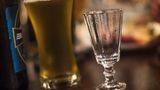 Ein volles Bierglas neben einem leeren Vodka-Glas