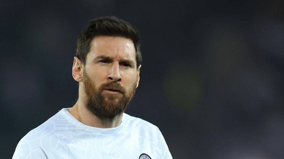Lionel Messi geht im Trainingsdress von PSG mit ernstem Gesicht über einen Fußballplatz
