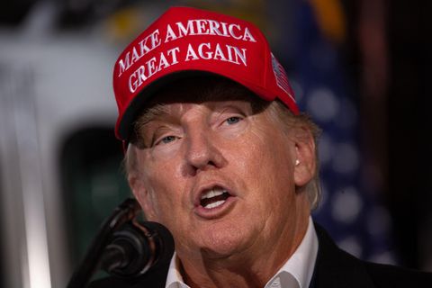 Donald Trump spricht mit roter "Make America great again"-Mütze auf dem Kopf in ein Mikrofon