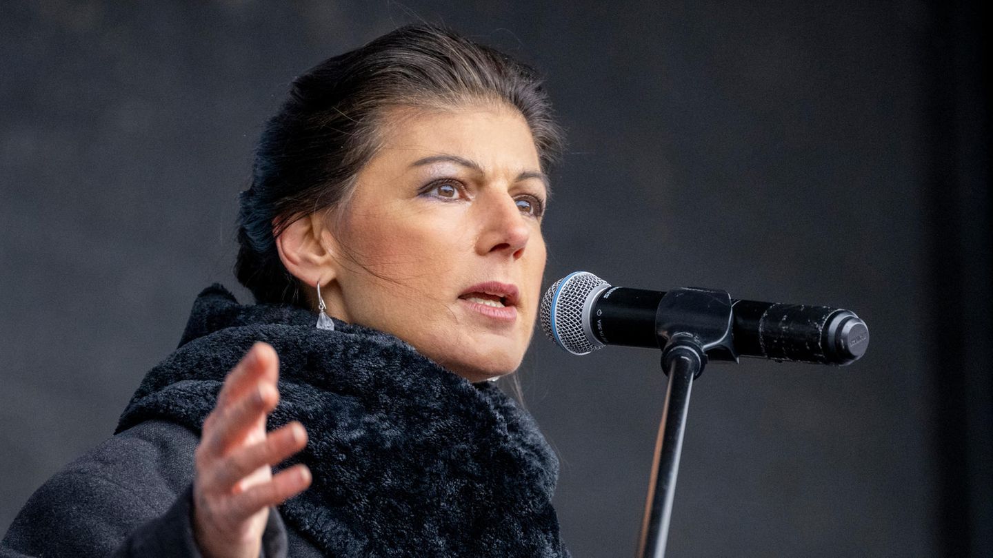 Sahra Wagenknecht stands dressed in black and gestures while speaking into a microphone