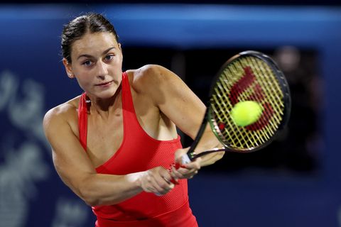 Marta Kostjuk, eine weiße junge Frau mit braunen Haaren, schlägt in rotem Top eine Rückhand beim Tennis