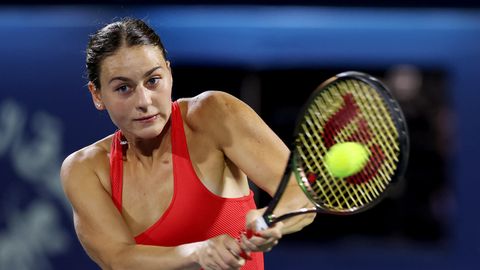 Marta Kostjuk, eine weiße junge Frau mit braunen Haaren, schlägt in rotem Top eine Rückhand beim Tennis