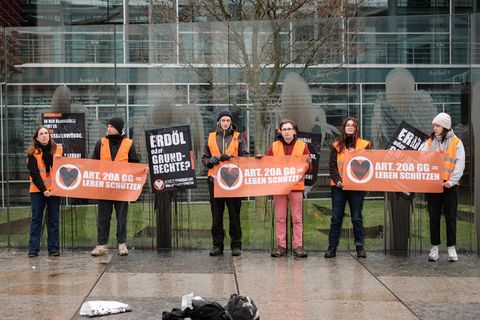 Aktivisten der Letzten Generation halten Protestschilder vor dem Grundgesetz-Denkmal in die Höhe