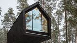 Dieses Modell ist kein privates Haus, sondern Teil des Kivijärvi Resorts. Wegen des Salamajärvi-Nationalparks musste es sorgfältig geplant werden, um die Natur zu schonen. Die Architekten entschieden sich für drei Unterkunftsvarianten. Der hier gezeigte Prototyp ist vom Boden angehoben. Das Bauwerk balanciert auf einem einzigen Pfeiler. Durch das raumhohe Fenster lässt sich die Landschaft überblicken. 