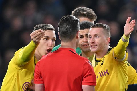 Die Dortmunder Nico Schlotterbeck (links) und Marco Reus reden auf Schiedsrichter Danny Makkelie ein.