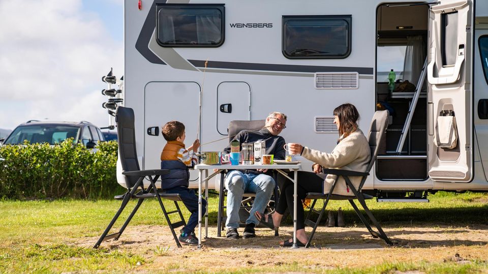 Redakteur Gunnar Herbst, seine Frau und ihr Sohn sitzen an einem Campingtisch vor ihrem Wohnmobil und essen