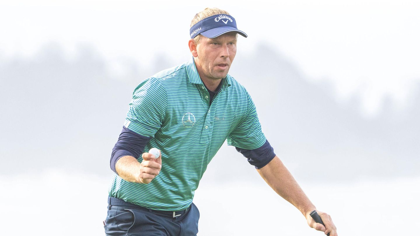 Marcel Siem trägt eine Schirmmütze und hält einen Golfball in der Hand