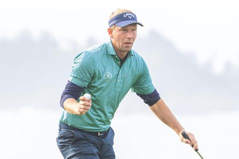 Marcel Siem trägt eine Schirmmütze und hält einen Golfball in der Hand