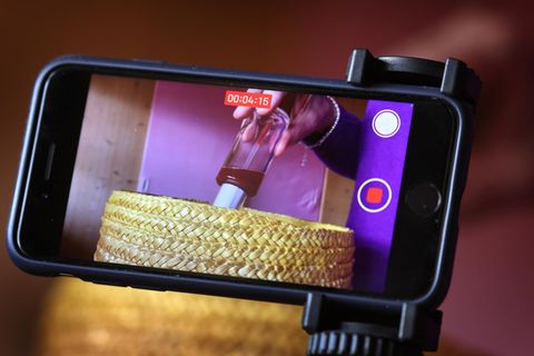 Eine Frau wirft ein Pflegeprodukt in einen Abfallbehälter und nimmt die Szene mit einem iPhone auf