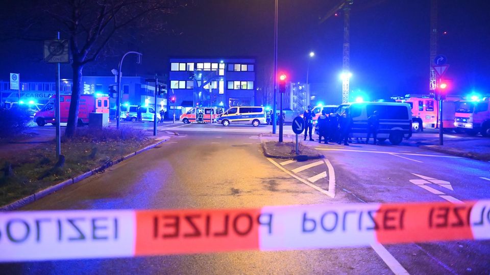 Am Tatort eines Amoklaufes in Hamburg überspannt rot-weißes Absperrband der Polizei eine mehrspurige Straße voller Polizeiautos