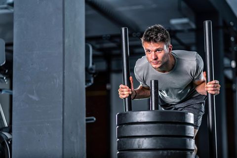 Hyrox-Training: Ein Sportler schiebt einen mit Gewichten beladenen Schlitten