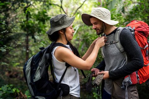 Eine Frau und ein Mann stehen im Wald und gehen wandern