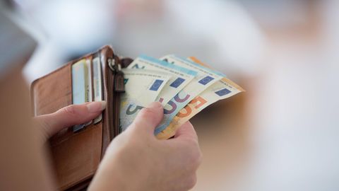 Frau zückt Geldscheine aus ihrem Geldbeutel. Symbolbild für den Artikel zur Energiepauschale