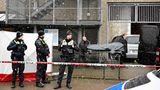 Zwei Bestatter rollen eine Bahre mit schwarzem Leichensack darauf zu ihrem Transporter