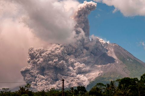 Im Sonnenschein steigt eine gigantische Aschewolke über einem Berg auf