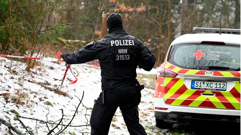 Bei Freudenberg geht ein Polizist mit rot-weißem Absperrband an einer verschneiten Böschung entlang
