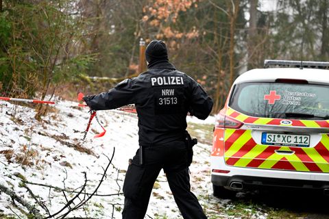 Bei Freudenberg geht ein Polizist mit rot-weißem Absperrband an einer verschneiten Böschung entlang