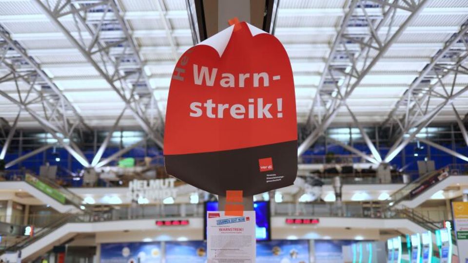 Ein Plakat mit dem Text ·Warnstreik!· hängt im menschenleeren Terminal 2 im Flughafen Hamburg