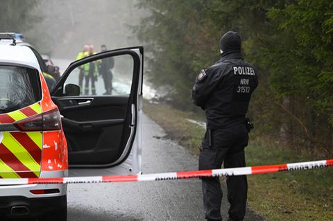 Einsatzkräfte der Polizei stehen nahe des Fundorts der Leiche an einer Absperrung