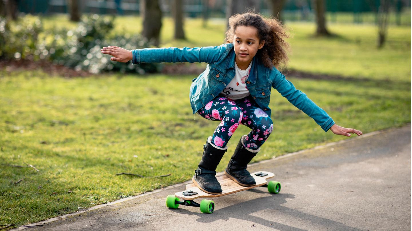 Skateboards für Kinder: So finden Sie das richtige Modell Skateboards für Kinder: Mädchen übt mit Schutzausrüstung in einem Park
