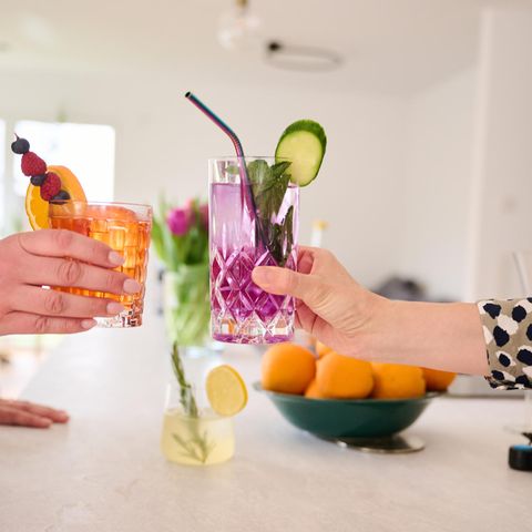 Zwei Frauen stoßen mit Cocktails ohne Alkohol (Aperol Spritz und Gin Tonic) an