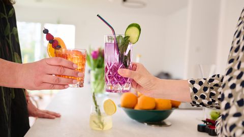 Zwei Frauen stoßen mit Cocktails ohne Alkohol (Aperol Spritz und Gin Tonic) an