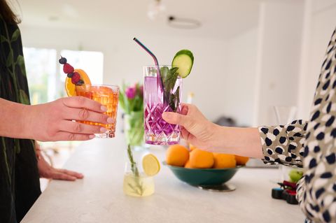 Zwei Frauen stoßen mit Cocktails ohne Alkohol (Aperol Spritz und Gin Tonic) an