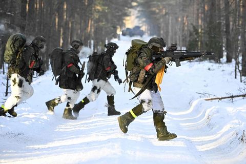 Ein Bundeswehrsoldat läuft über eine schneebedeckte Straße