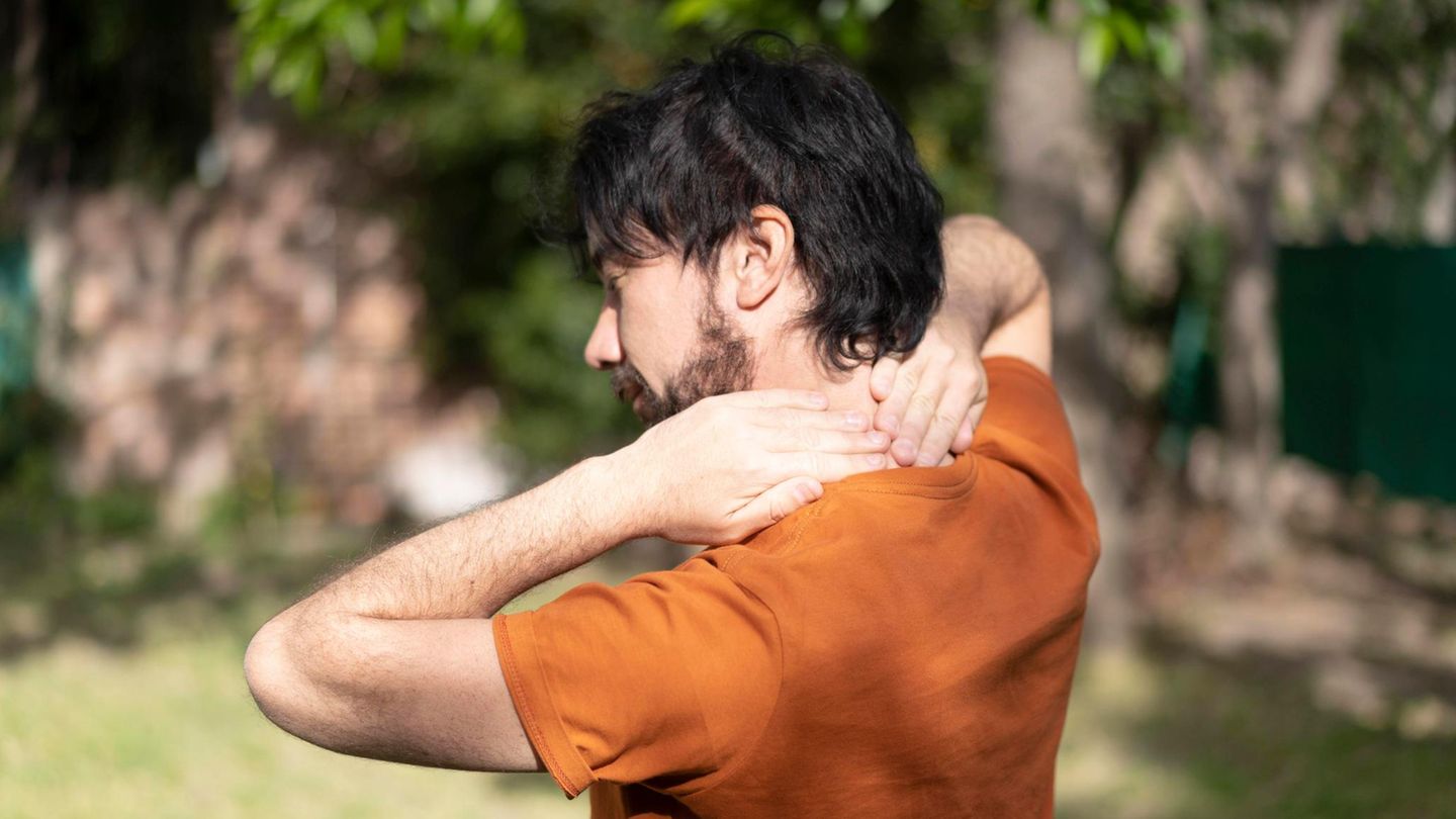 Ein Mann massiert sich den eigenen Nacken wegen Rückenschmerzen