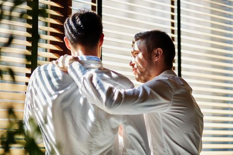 Zwei Männer stehen nebeneinander, einer legt unterstützend die Hand auf die Schulter des anderen