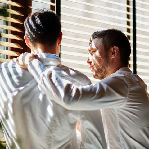 Zwei Männer stehen nebeneinander, einer legt unterstützend die Hand auf die Schulter des anderen