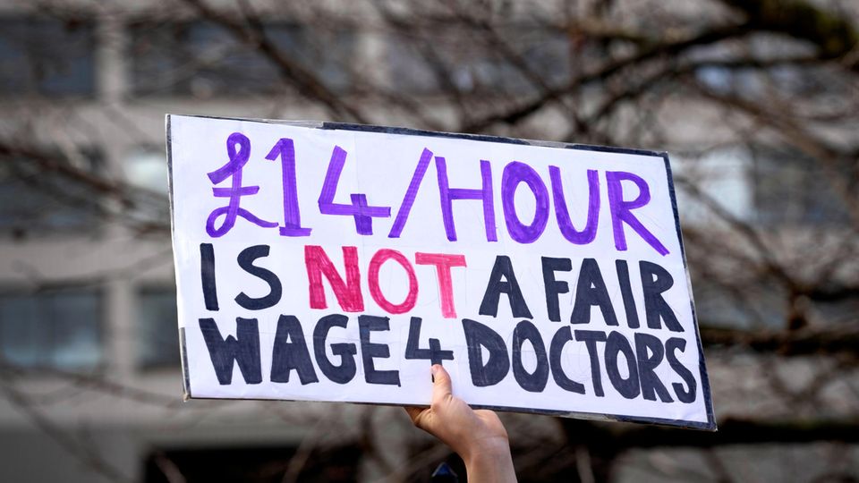Ärzte des britischen Gesundheitssystems streiken, auf diesem Schild steht: "14 Pfund ist kein fairer Stundenlohn für Ärzte".