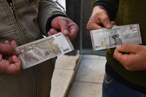 Inflation Syrien: Zwei Männer halten Banknoten in die Kamera