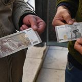 Inflation Syrien: Zwei Männer halten Banknoten in die Kamera