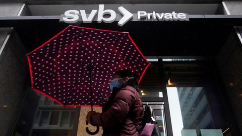 Eine Fußgängerin geht mit einem Regenschirm an einer Filiale der Silicon Valley Bank vorbei