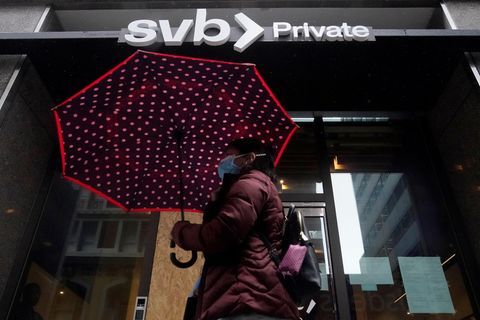 Eine Fußgängerin geht mit einem Regenschirm an einer Filiale der Silicon Valley Bank vorbei