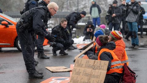 Polizisten reden mit Aktivistinnen der Letzten Generation, die sich auf der Fahrbahn der Jahnallee in Leipzig festgeklebt haben