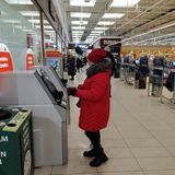 Inflation in Lettland. Eine Frau im Anorak gebt Geld ab