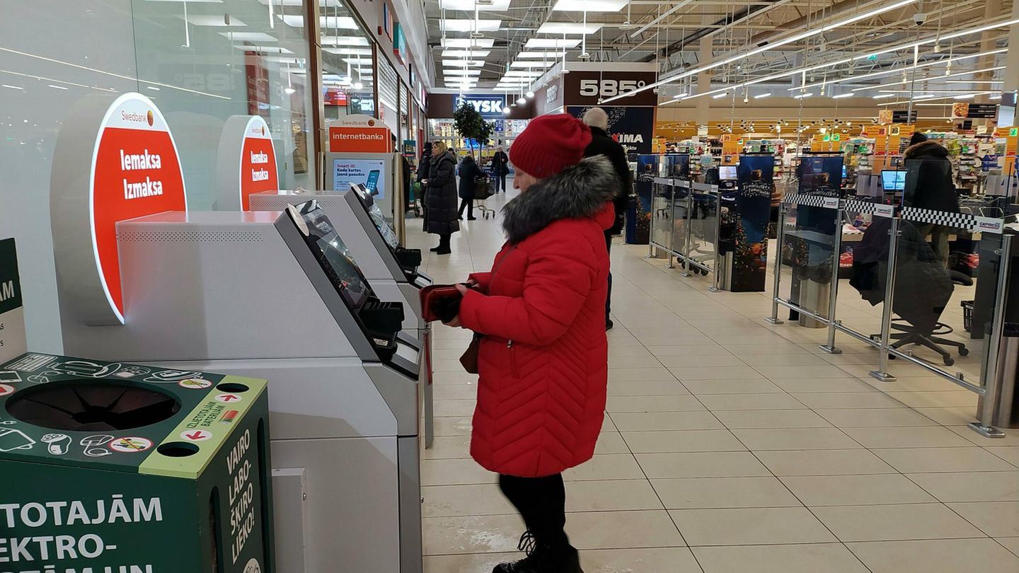 Inflation in Lettland. Eine Frau im Anorak gebt Geld ab Inflation in Lettland. Eine Frau im Anorak gebt Geld ab