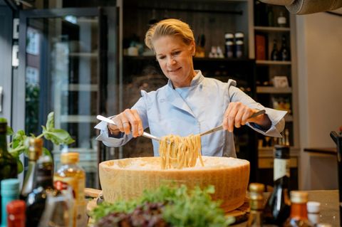 Cornelia Poletto wendet Pasta in einem riesigen Parmesanlaib