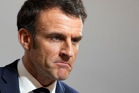 Emmanuel Macron, ein weißer Mann mit braunem Seitenscheitel, trägt blauen Anzug und Krawatte und schaut skeptisch