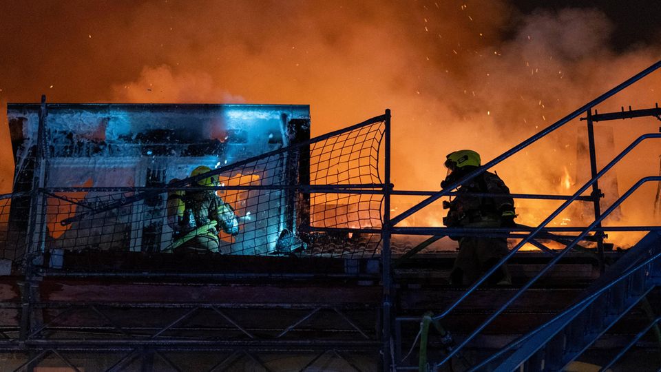 Zwei Feuerwehrleute auf brennendem Haus