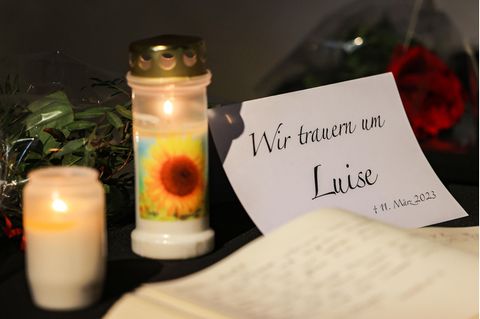 Neben einem Blatt Papier mit "Wir trauern um Luise"-Aufdruck liegt ein Kondolenzbuch