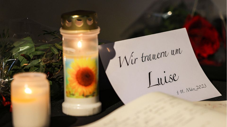 Neben einem Blatt Papier mit "Wir trauern um Luise"-Aufdruck liegt ein Kondolenzbuch